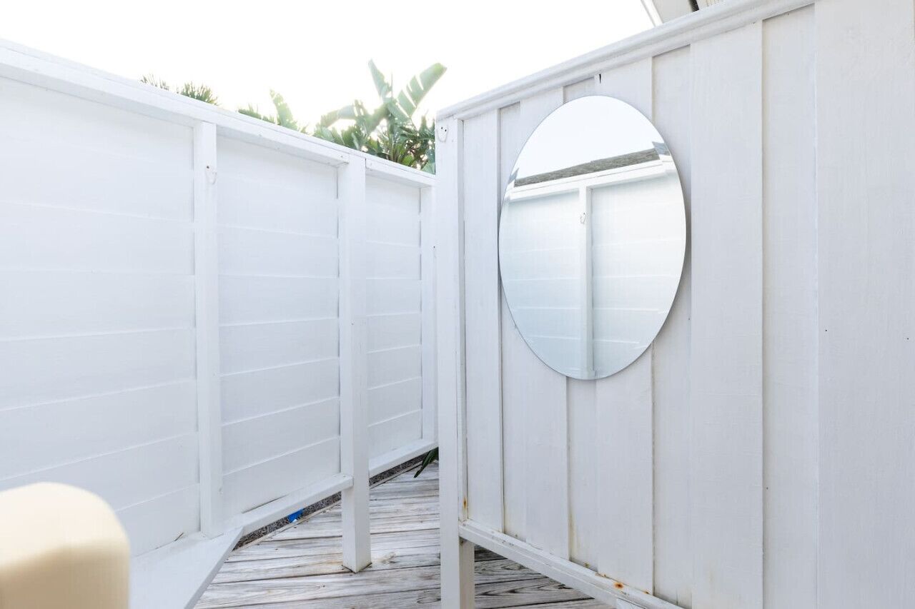 A white wooden fence with a circular mirror mounted on it.