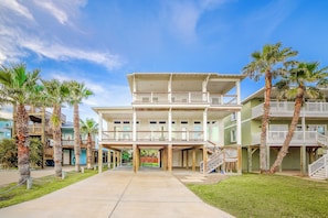 A multi-story hotel with a central courtyard, palm trees, and a clear sky. - Gone Coastal - Ocean Views! (Port Aransas)