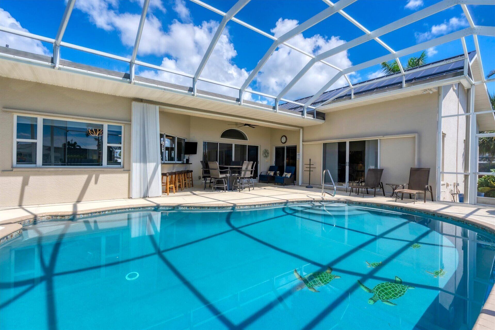 A swimming pool with a glass ceiling, lounge chairs, and a bar area.