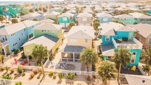 Ett bostadsområde vid kusten med färgglada hus, en sandstrand och palmer.