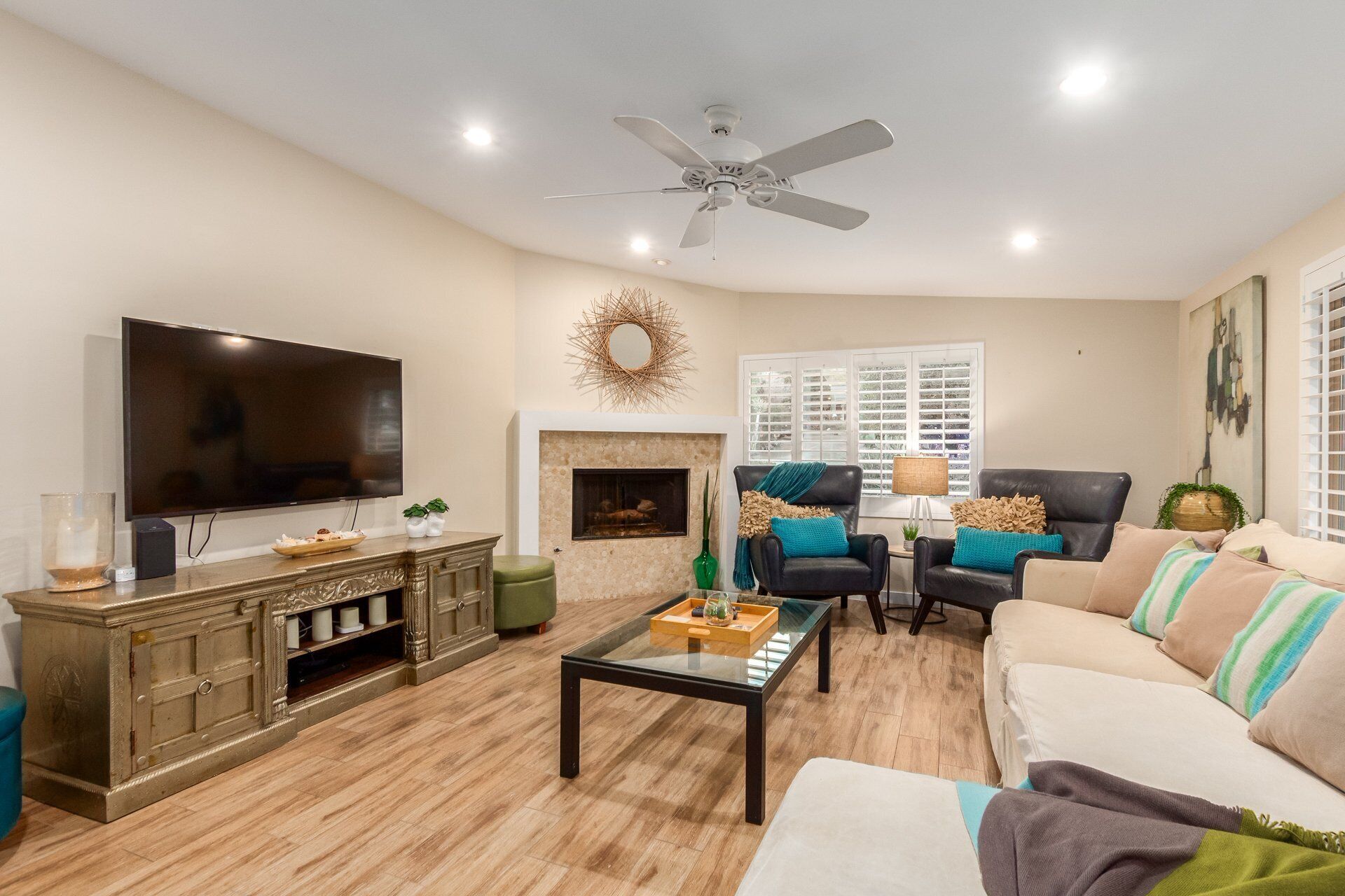 A living room with a television, fireplace, ceiling fan, and seating area.