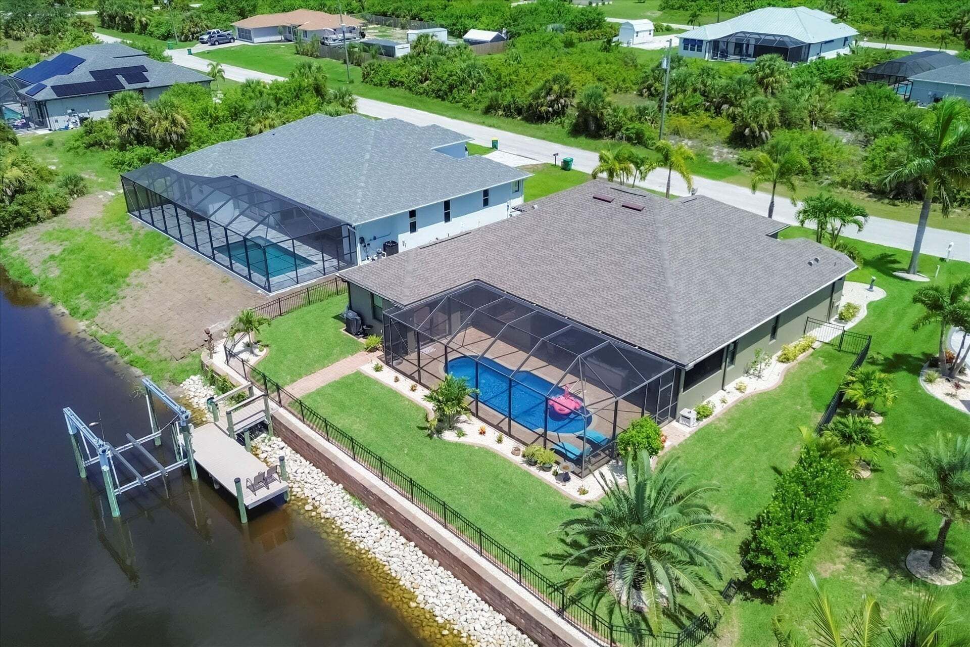 Ein Wohnhaus mit Swimmingpool, überdachter Terrasse und einer Anlegestelle, die ins Wasser führt.
