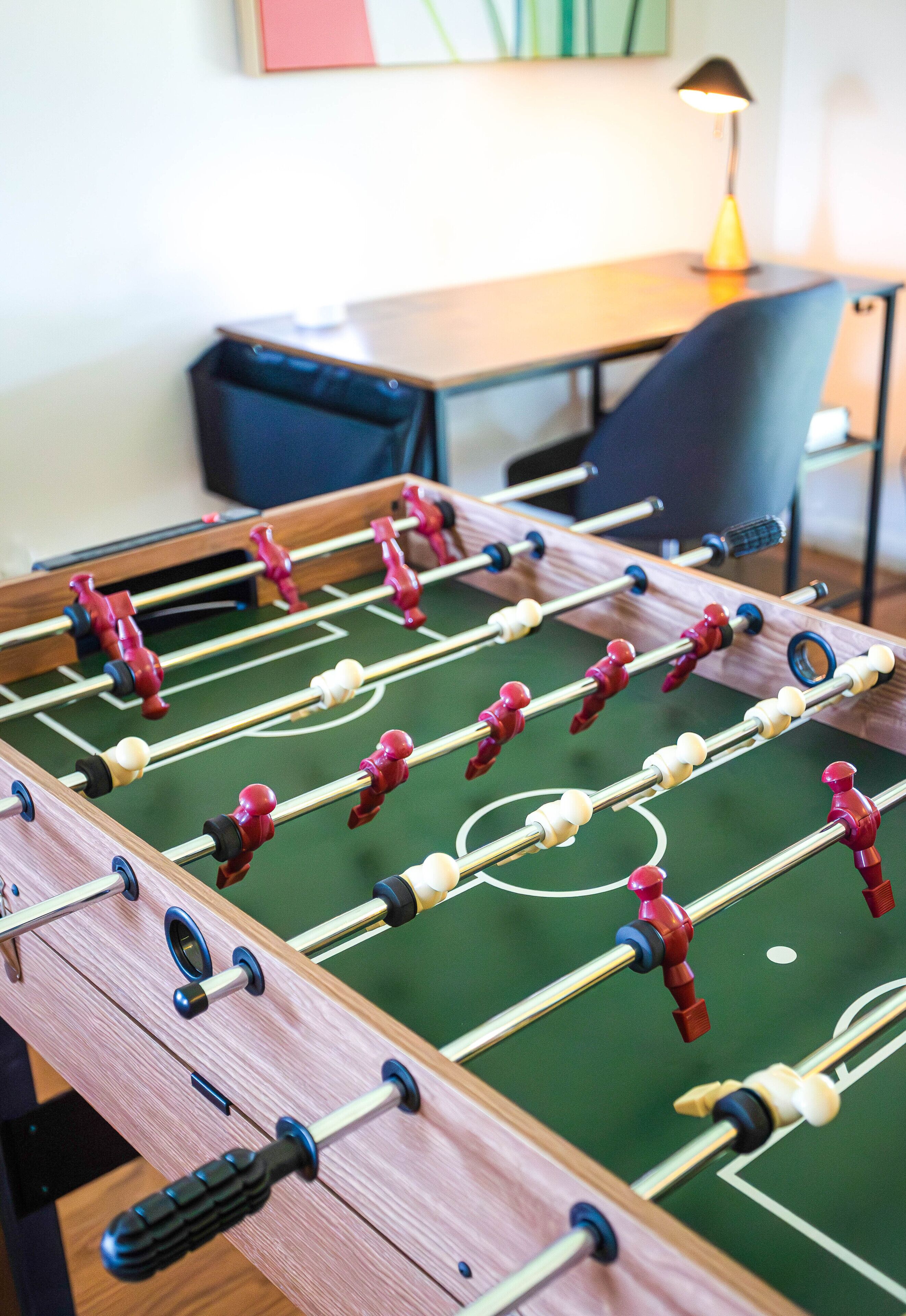 Una mesa de fútbol de mesa en una habitación con un escritorio y una silla al fondo.