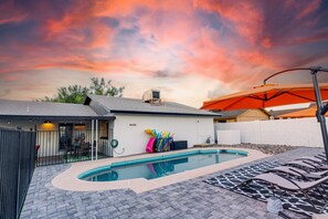 A backyard with a swimming pool, a covered patio area, and a fenced play area. - Campbell Phoenix (Phoenix)