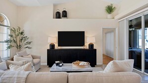 A living room with a sofa, a coffee table, a TV, and a plant. - Gic120 (Punta Gorda)