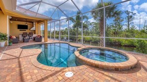 Zona de piscina con jacuzzi, mobiliario exterior y vistas a un paisaje natural.