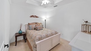 A bedroom with a bed, a nightstand, a lamp, a ceiling fan, and a decorative wall piece. - Ppm3329-112 (Punta Gorda)