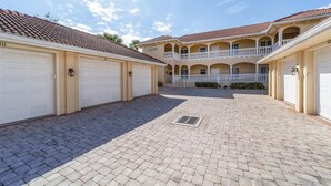 A courtyard with a paved floor, multiple garage doors, and a two-story building with balconies. - Ppm3329-112 (Punta Gorda)