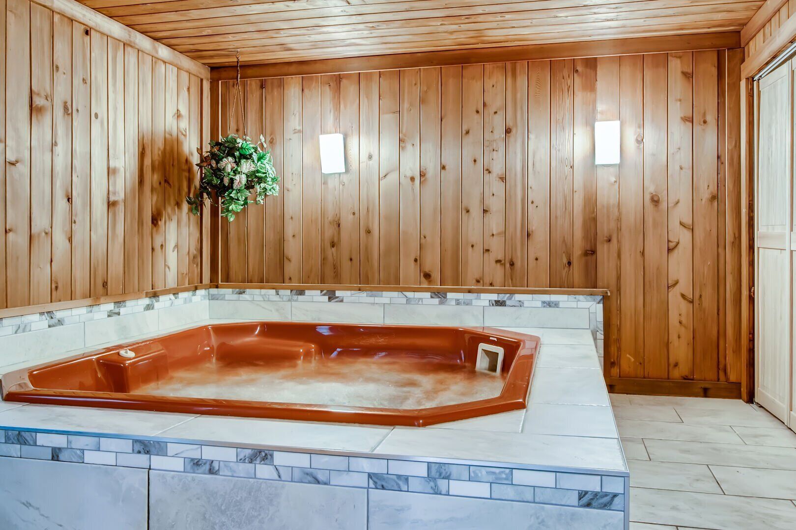 Un cuarto de spa con interiores de madera, un amplio jacuzzi y piso de baldosas.