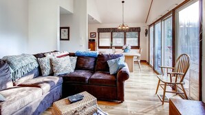 Ein Wohnzimmer mit braunem Ledersofa, einem Holzesstisch und einem großen Fenster mit Blick.