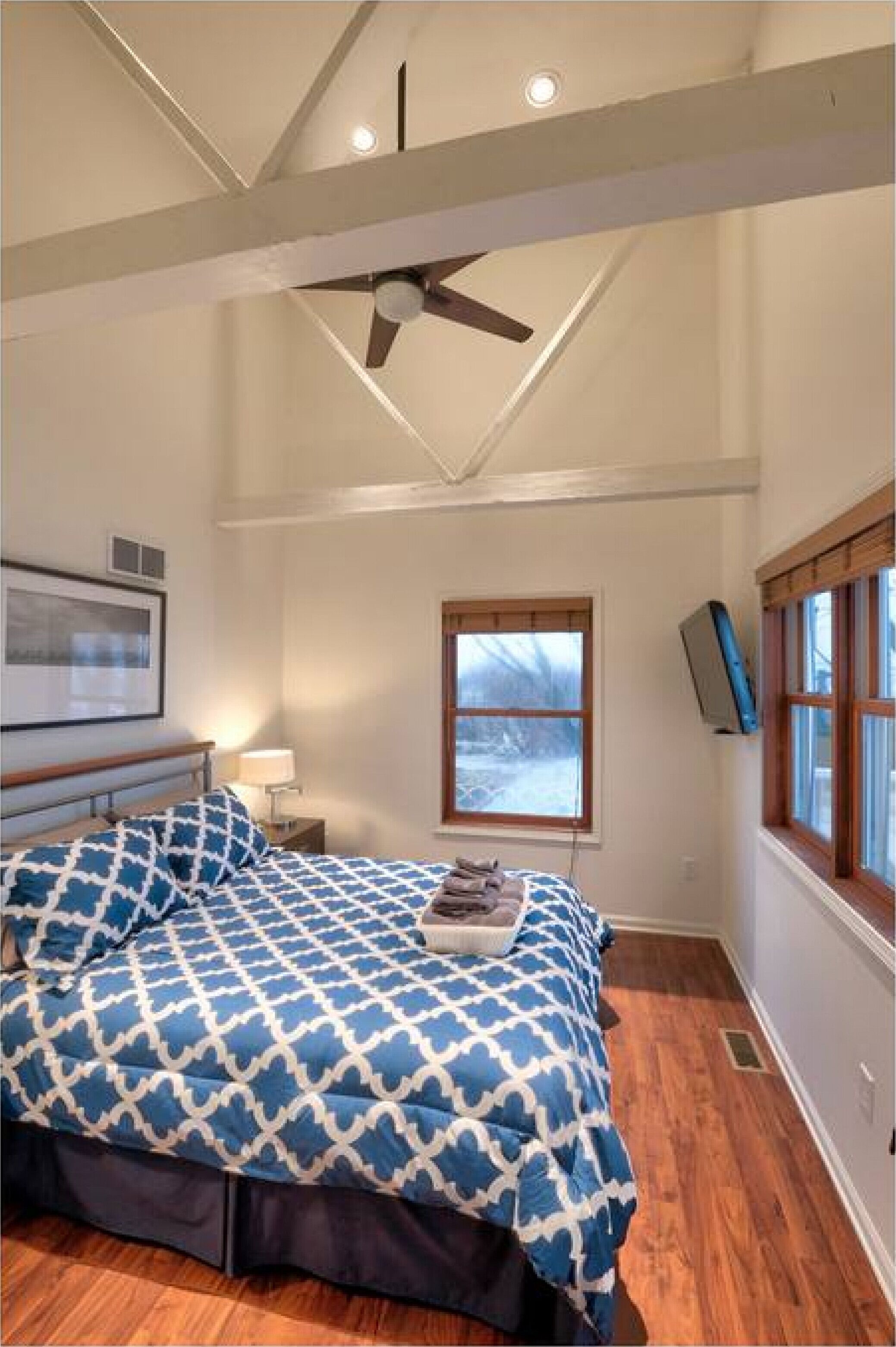 Ein Schlafzimmer mit einem Bett, einem Deckenventilator, einem Fenster und einem gerahmten Bild an der Wand.