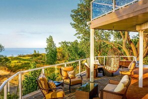 Une terrasse dotée de meubles en osier, d’un fauteuil suspendu et offrant une vue sur l’océan.