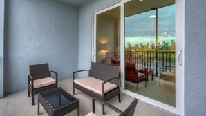Un balcon agrémenté de meubles en osier, une porte vitrée donnant sur un espace extérieur aménagé avec vue sur le paysage.