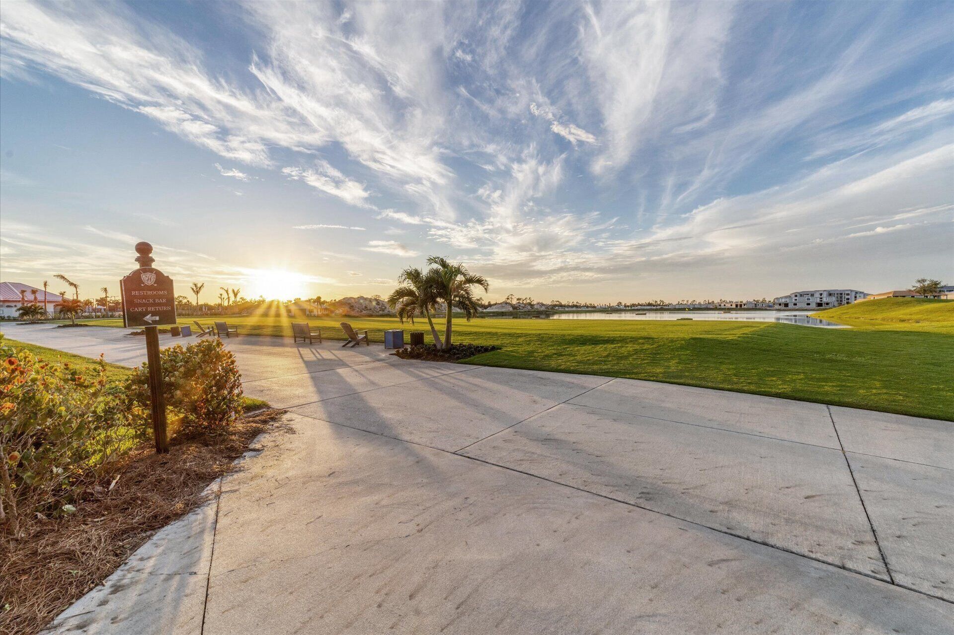 A pathway leading to a snack bar and restrooms, with a view of a golf course and buildings in the distance.