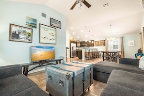 A living room with a television, a dining area, and a kitchen. - Boogie Board Bungalow - Pet Friendly! Private Pool! 2 (Port Aransas)