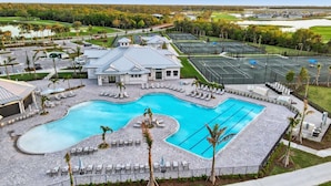 A large swimming pool with multiple sections, surrounded by lounge chairs and palm trees. - Cbw14724 (Punta Gorda)