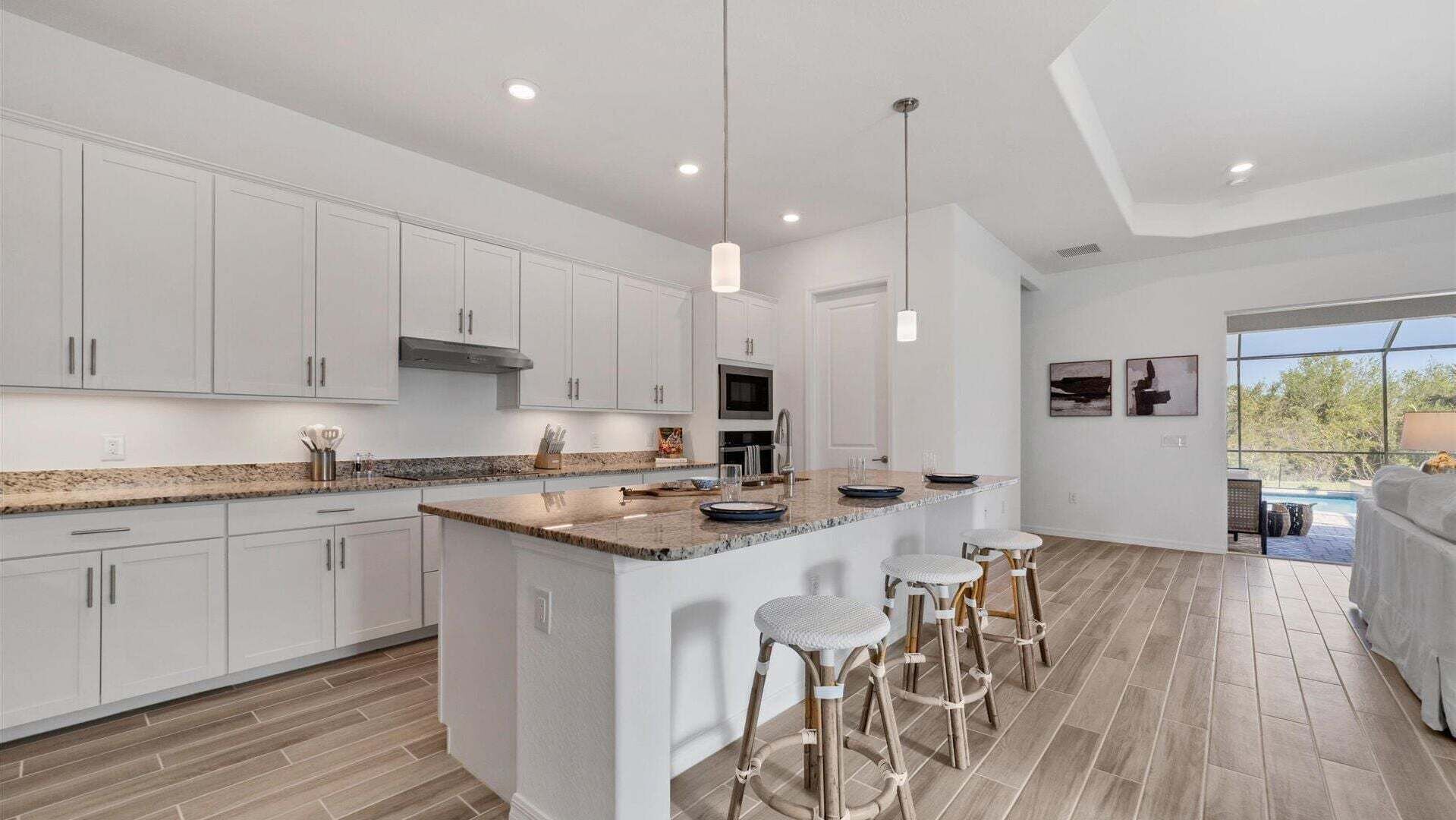A modern kitchen with white cabinets, a granite countertop, and a central island with bar stools.