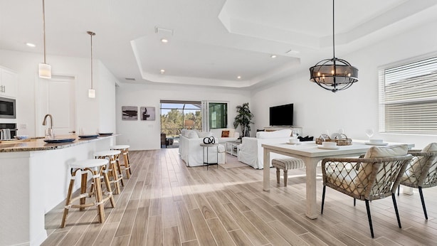 A modern kitchen with a central island, bar stools, and a dining area with wicker chairs. - Cbw14724 (Punta Gorda)