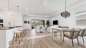 A modern kitchen with a central island, bar stools, and a dining area with wicker chairs. - Cbw14724 (Punta Gorda)