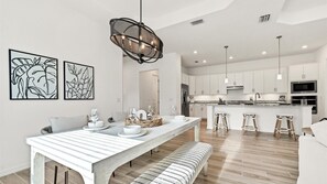 A modern kitchen with white cabinets, stainless steel appliances, and a central island with stools. - Cbw14724 (Punta Gorda)