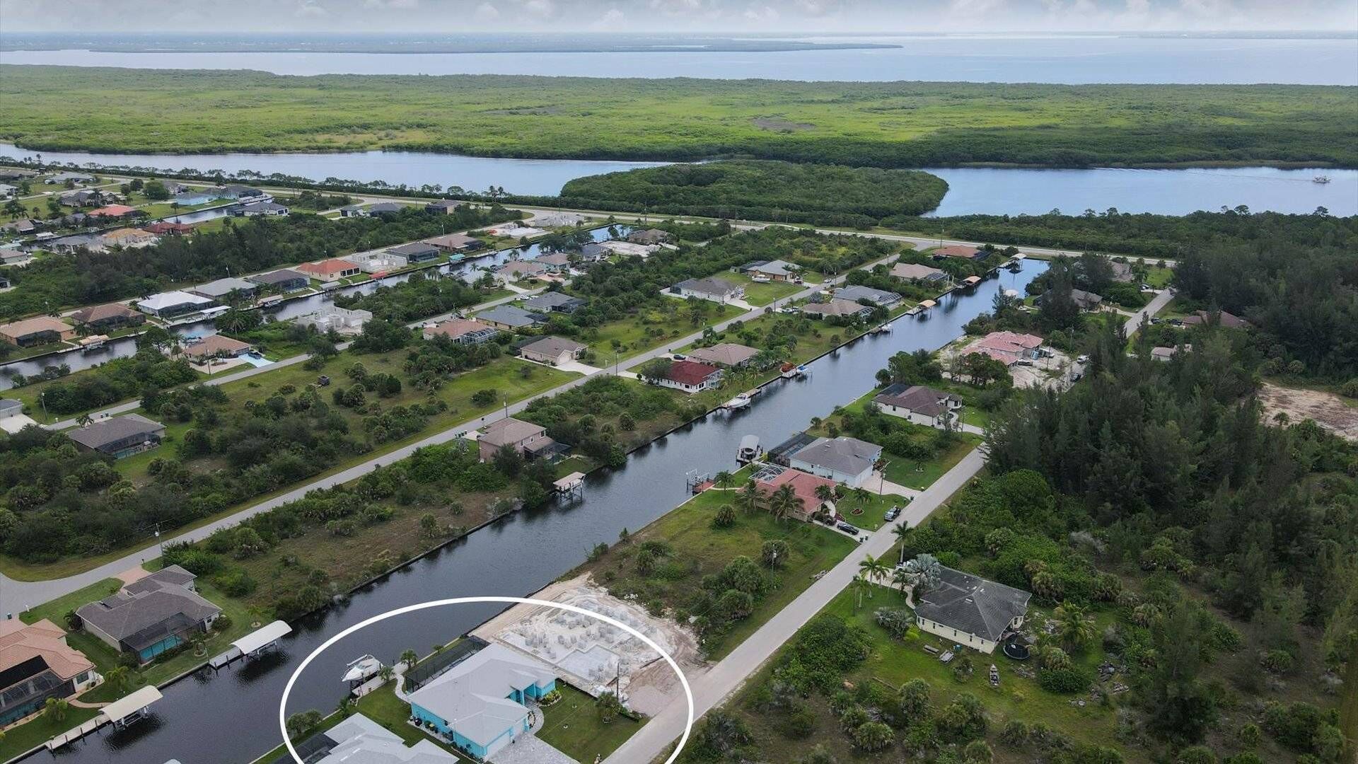 Vue aérienne d’un quartier résidentiel avec des maisons, un canal et une grande étendue d’eau en arrière-plan.