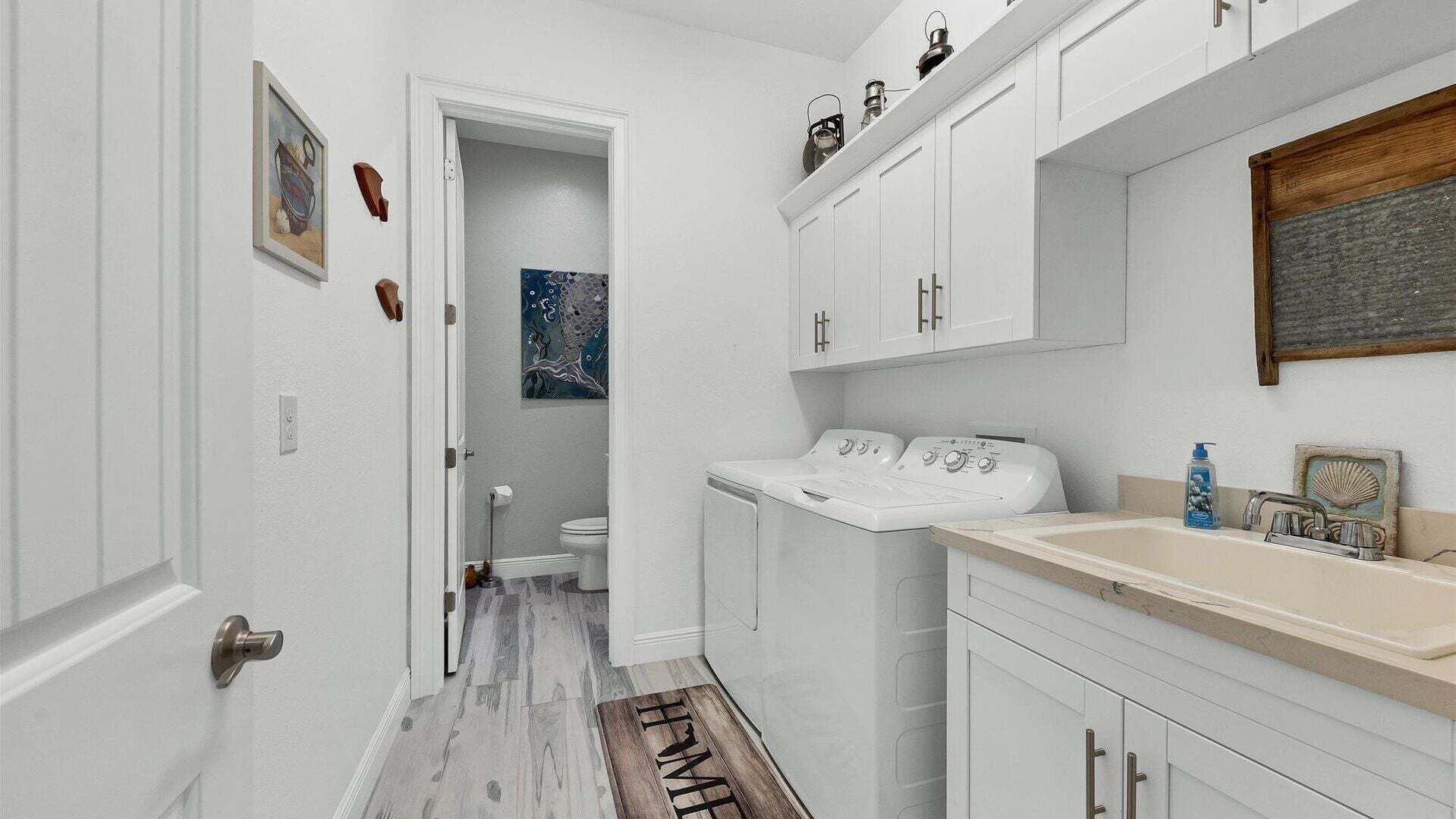 Een smalle gang die leidt naar een badkamer met een toilet, een wasmachine en een wastafel met een spiegel erboven.