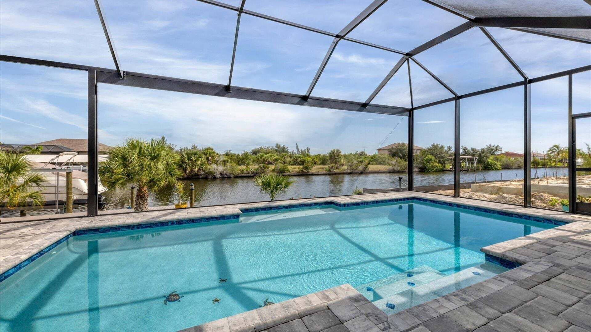 Una piscina con vistas a un río y árboles, rodeada por una estructura de cristal.