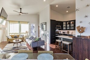 A modern living room with a sofa, coffee table, and a dining area with stools. - Elk Rim 1140 Pine (Pine)