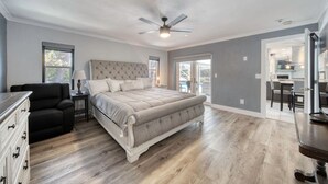 A spacious bedroom with a large bed, a ceiling fan, and a view of the patio. - Lighthouse Retreat With A Pool (Ponce Inlet)