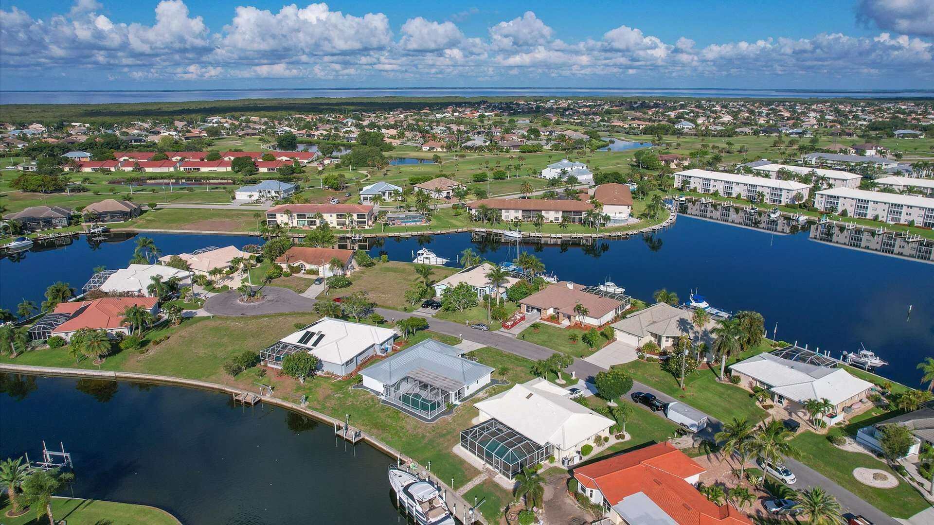 An aerial view of a residential area with houses, a marina, and a large body of water.