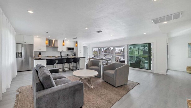 A modern kitchen with white cabinets, a stainless steel refrigerator, and a dining area with a round table and two chairs. - Kld1521 (Punta Gorda)