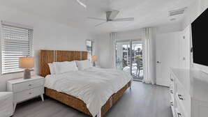 A modern bedroom with a large bed, a ceiling fan, and a view of a pool through a glass door. - Kld1521 (Punta Gorda)