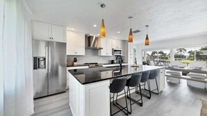 A modern kitchen with a central island, stainless steel appliances, and pendant lighting. - Kld1521 (Punta Gorda)