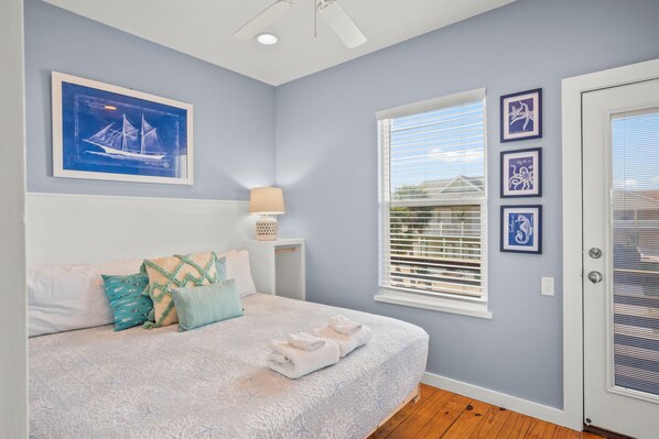 A bedroom with a bed, a window with blinds, and wall art. - No Regrets! PET Friendly! (Port Aransas)