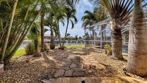 A tropical garden with palm trees, a stone pathway, and a glass conservatory. - Npl829 (Punta Gorda)