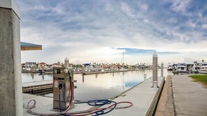 A marina with boats docked, a fuel pump, and a calm water body. - Marina Del Bell - Elevator! Boat Slip for Rent! (Port Aransas)
