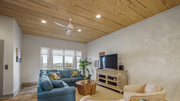A spacious living room with a wooden ceiling, a large TV, and a sofa set. - Marina Del Bell - Elevator! Boat Slip for Rent! (Port Aransas)