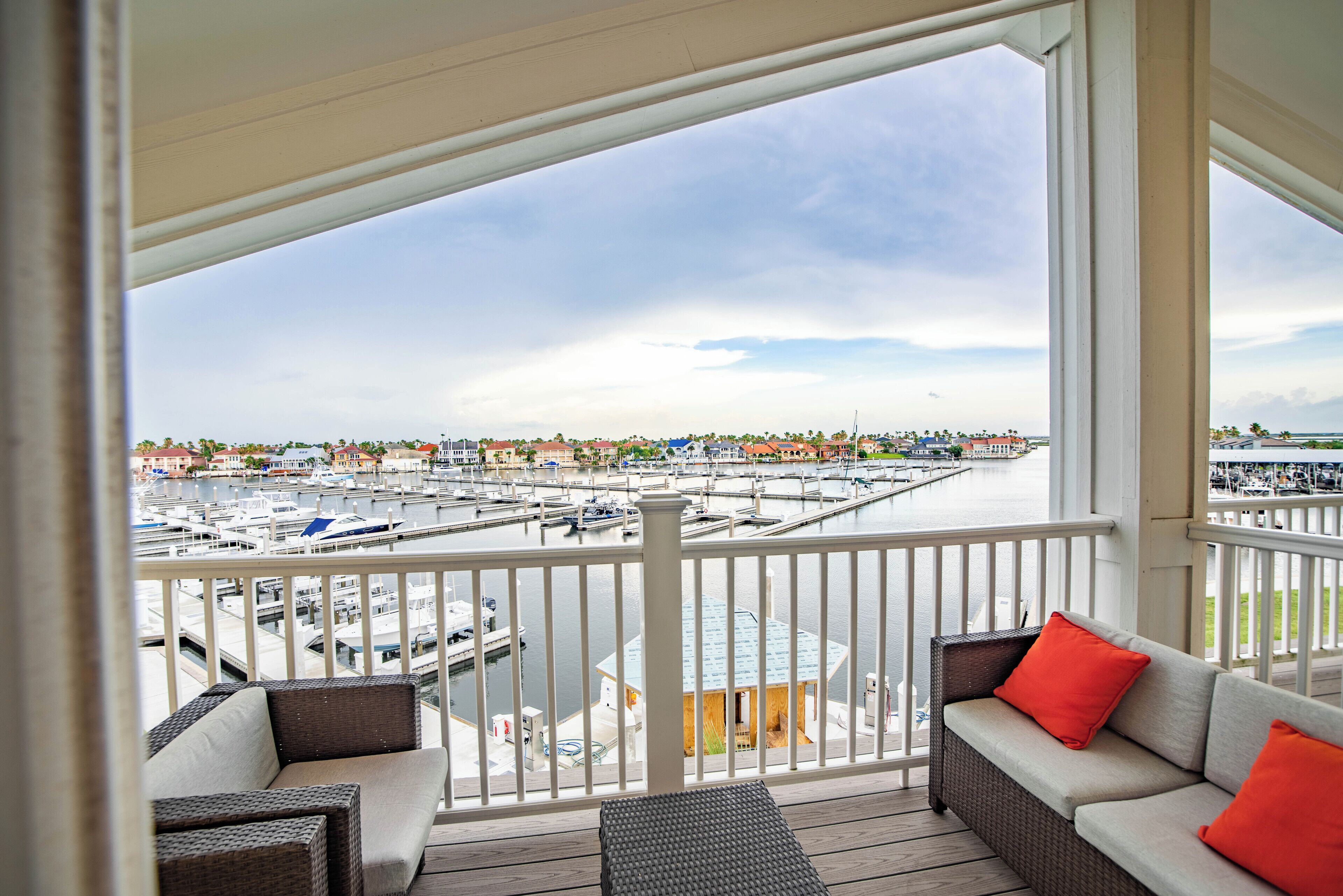A balcony with wicker furniture and a view of a marina with boats.