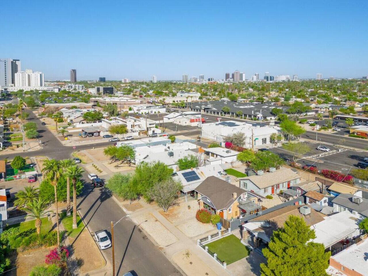 An aerial view of a residential area with houses, streets, and distant city buildings.