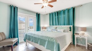 Ein Schlafzimmer mit Bett, Stuhl, Nachttisch, Lampe und Deckenventilator.