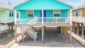 Ein türkisfarbenes, zweistöckiges Haus mit Balkon und blauer Tür.