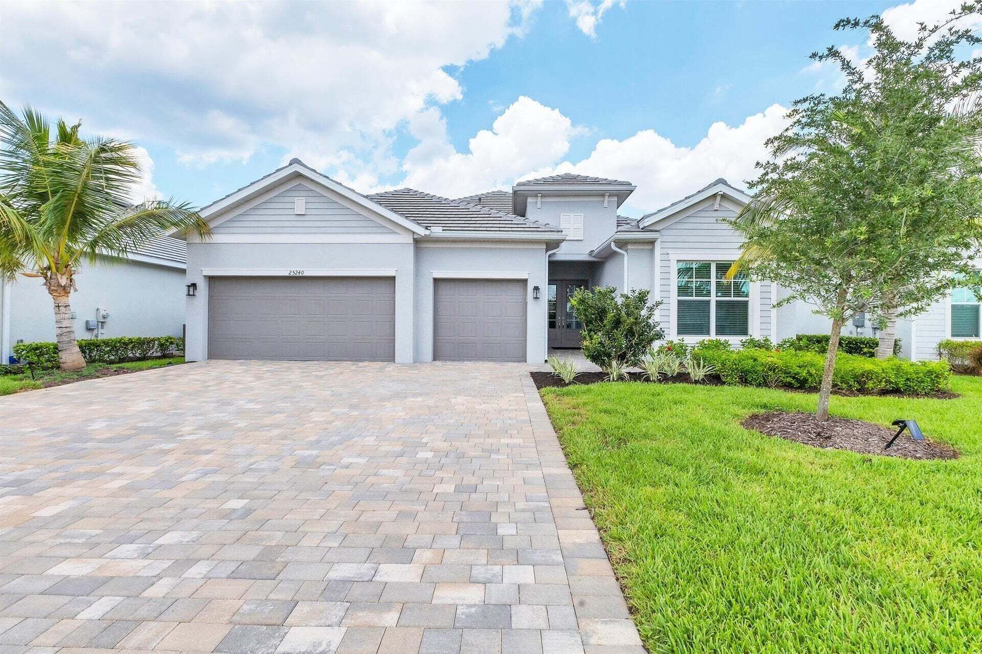 A modern two-story house with a paved driveway, a garage, and a well-maintained lawn.