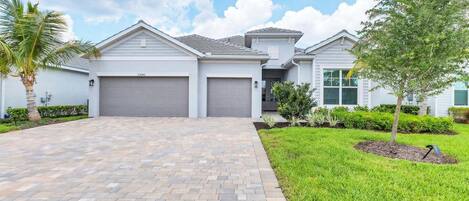 A modern two-story house with a paved driveway, a garage, and a well-maintained lawn.