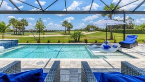 A swimming pool with lounge chairs and an umbrella, surrounded by a covered area with a view of a golf course. - Heritage Landing Haven Resort Amenities + Golf Membership (Punta Gorda)