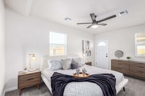 A bedroom with a bed, bedside tables, a ceiling fan, a door, and a window. - Dayton Coronado Historic District Phoenix (Phoenix)