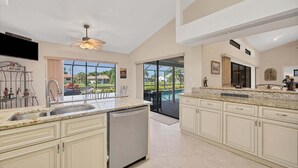 A spacious kitchen with a large island, a dishwasher, and a view of a swimming pool. - Lpc1140 (Punta Gorda)