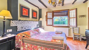 Une chambre à coucher avec un grand lit, un bureau avec une lampe, une chaise et une fenêtre avec des stores.