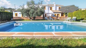 Une piscine dotée d’une terrasse carrelée, entourée d’une clôture en bois et d’une pelouse.
