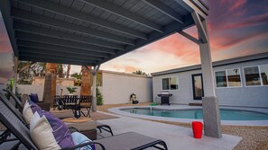 A covered patio with outdoor furniture, a pool, and a house in the background. - Heatherbrae Phoenix (Phoenix)