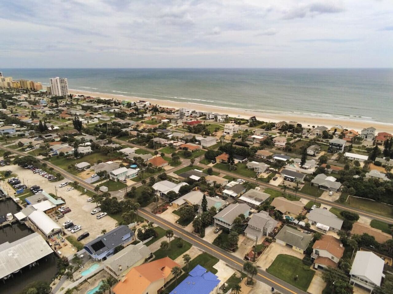 An aerial view of a coastal residential area with houses, roads, and a beach.